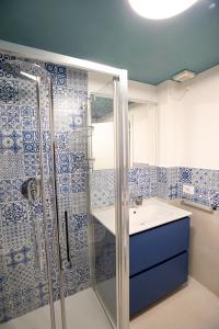une salle de bain bleue et blanche avec une douche et un lavabo dans l'établissement La Scarpa della Strega, à Chioggia
