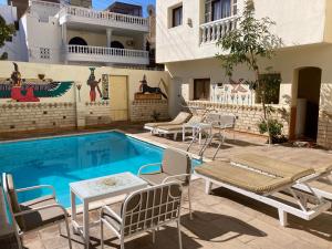 a swimming pool with chairs and a house at Memnon Apartments in Luxor