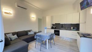 Una sala de estar con un sofá y una mesa y una cocina. en Blu Caletta - waterfront apartment with garden, en La Caletta