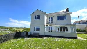 a white house with a fence in the grass at Fairlee in Perranporth