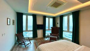 a bedroom with a bed and chairs and large windows at Elegant Gold crest mall apartment with Grand Alfateh store in Lahore