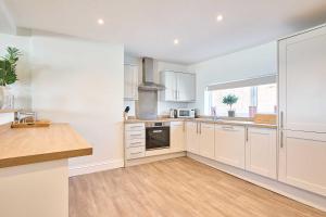 a large kitchen with white cabinets and a window at Host & Stay - Albert House in Weymouth