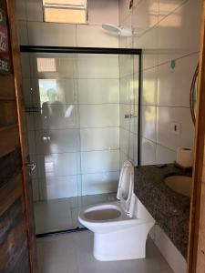 a bathroom with a toilet and a glass shower at Pousada Refúgio das Águas Quarto 2 in Chapecó