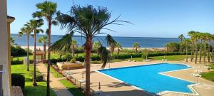 widok na basen z palmami i ocean w obiekcie WIFI Los Cisnes 2 dormitorios Primera Linea playa Ayamonte Isla Canela w mieście Isla Canela