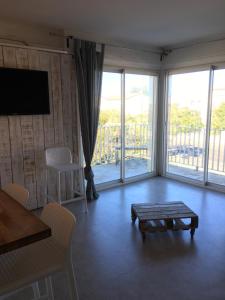 Una sala de estar con una mesa y una gran ventana. en Acces Direct Plage, Vue Mer, Climatisation, en La Celle-sous-Gouzon