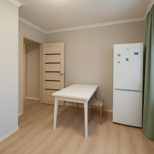 a kitchen with a white table and a refrigerator at Уютная квартира с видом на лес рядом с Боровым и Rixos in Shchūchīnsk