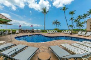 a swimming pool with lounge chairs and palm trees at Island Sands 600 by Coldwell Banker Island Vacations in Maalaea