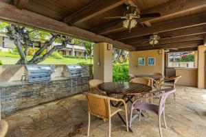 a patio with a table and chairs and a ceiling fan at Kaanapali Royal N202 by Coldwell Banker Island Vacations in Lahaina