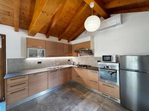 a kitchen with wooden cabinets and a stainless steel refrigerator at Casa Mariett Gravedona - Larihome A92 in Gravedona