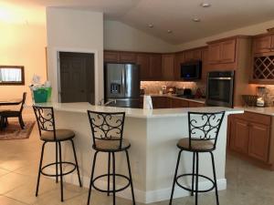 a kitchen with three bar stools and an island in the middle at 2964 Z6 VILLAGE OF FENNEY by REMAX Premier in The Villages +18 photos
