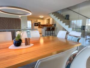 Un comedor con una mesa de madera y sillas blancas. en "GLÜCKSMOMENT" - Premium Apartments Seekirchen, beeindruckende Ferienwohnung mit gemeinsam genutzter Poolarea, en Seekirchen am Wallersee