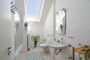 a bathroom with a sink and a toilet and a window at Sky Loft Leipzig - moderne Dachwohnung mit Terrasse und Blick aufs Rathaus in Leipzig +12 photos