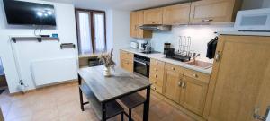a kitchen with a wooden table and a small table with a laptop at Le Cocon d'Estoublon in Estoublon