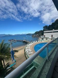 balcón con piscina y playa en angra dos reis, condomínio angra inn, en Angra dos Reis