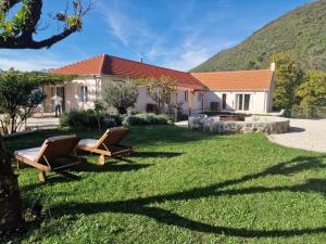 a house with two chairs in the yard at Villa Antonia in Tivat