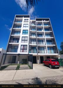 ein rotes Auto, das vor einem Gebäude geparkt ist in der Unterkunft Hermoso Apartamento con piscina in La Playa Bejarano + 13 Fotos