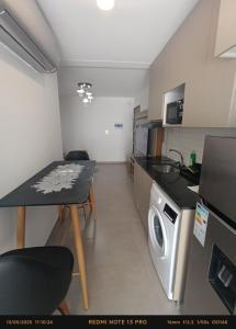 eine kleine Küche mit einem Tisch und einer Waschmaschine in der Unterkunft Hermoso Apartamento con piscina in La Playa Bejarano