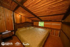 a bed in a room with a wooden ceiling at Hospedaje rural Casa del Viejo in Tibaná