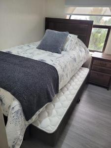 a bedroom with a bed with a white mattress and a window at Departamento Plaza Río Bueno in Río Bueno