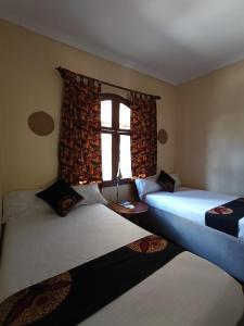two beds in a room with a window at Hansat Homestay Residence in Arusha