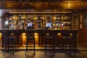a bar with three bar stools in a room at New Inn Hotel in Ellon