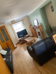 a living room with a leather couch and a television at Llwyn Celyn 2 bedroom in Bala
