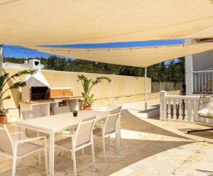 a patio with a white table and chairs under a umbrella at Villa Prats Ibiza in Sant Josep