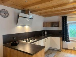 a kitchen with a stove and a clock on the wall at Appartamenti Daberto Fabiola in Arabba