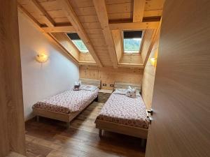 two beds in a small room with two windows at Appartamenti Daberto Fabiola in Arabba