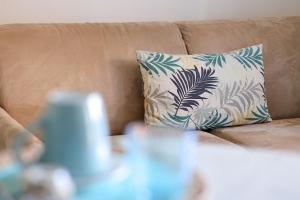 a pillow on a brown couch with a blue and white pillow at Casa Acqua Marina in Castiglione della Pescaia