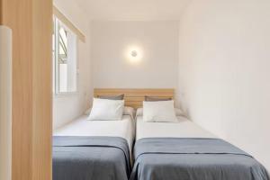 two beds sitting next to each other in a room at Apartamento Recién reformado con jardín en Arenal de Castell in Es Mercadal