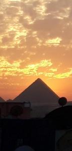 a silhouette of a pyramid with a sunset in the background at مفتاح الحياه in Banī Ghālib
