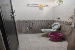 a bathroom with a toilet and a pink bucket at SPOT ON Sunrise Inn in Nagpur