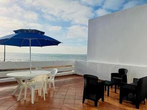 a patio with a table and chairs and an umbrella at Maison de plage pied dans l'eau pour familles in El Jadida