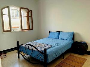 a bedroom with a bed with blue sheets and a window at Maison de plage pied dans l'eau pour familles in El Jadida