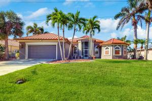 a house with palm trees in front of a yard at Cape Coral Charmer in Cape Coral