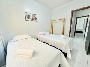 two beds in a white room with a mirror at Ap Conforto no Centro de Sinop in Sinop