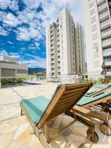 a couple of lounge chairs on a patio with buildings at Apartamento Mobiliado em Extrema MG in Extrema
