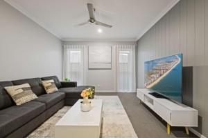 a living room with a couch and a flat screen tv at Modern 4BR Home Peaceful Logan Reserve Stay in Buccan