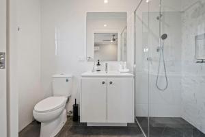 a white bathroom with a toilet and a shower at Modern 4BR Home Peaceful Logan Reserve Stay in Buccan +18 photos