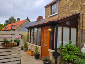 ein Haus mit einer Holztür und einem Zaun in der Unterkunft Gorgeous Two Bedroom Cottage, Pet Friendly! in Snainton