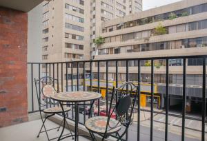 a table and chairs on a balcony with a bus at Aguirre By Wynwood House in Lima