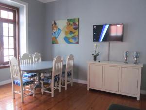 uma sala de jantar com mesa e cadeiras e uma televisão em Casa Azul Hostel em Sintra
