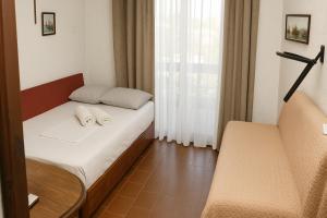a small bedroom with a bed and a window at StudioAretiCom Studio to rent in FRONT the lovely SEA fully equipped plagiastudioseu in Nea Plagia