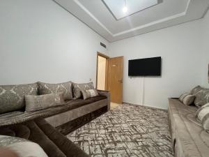 a living room with a couch and a flat screen tv at Bel appartement à deux pas de la plage in Agadir