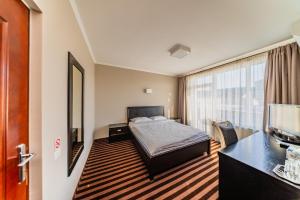 een slaapkamer met een bed, een bureau en een televisie bij Pensiunea Belanco in Arad