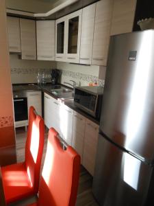 een keuken met een roestvrijstalen koelkast en rode stoelen bij Solar Golden Beach Apartments in Siófok