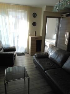 uma sala de estar com um sofá de couro e uma mesa de vidro em Solar Golden Beach Apartments em Siófok