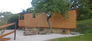 a wooden cabin with a tree in front of it at Les Roulottes des Bois d'Ormes in Bessey-en-Chaume