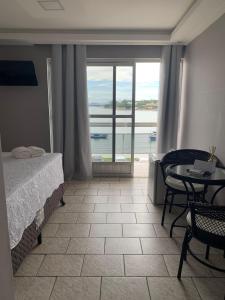 a bedroom with a bed and a table with a view at Casa pôr do sol in São Pedro da Aldeia